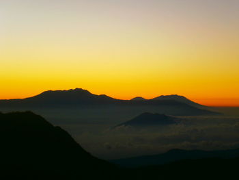 Scenic view of silhouette mountains against orange sky