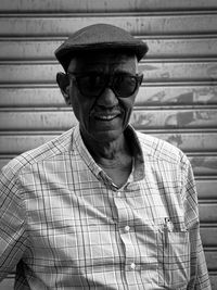 Portrait of old man wearing hat against wall