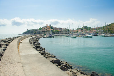 Sailboats moored at harbor against sky