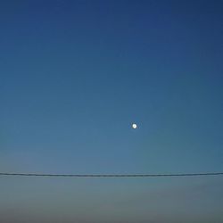 Low angle view of moon against clear blue sky