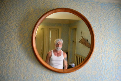 Portrait of man standing against mirror