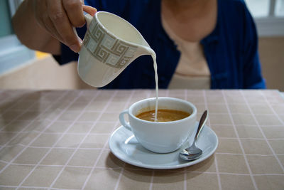 Midsection of woman holding coffee on table