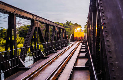 Train on railway bridge against sky during sunset