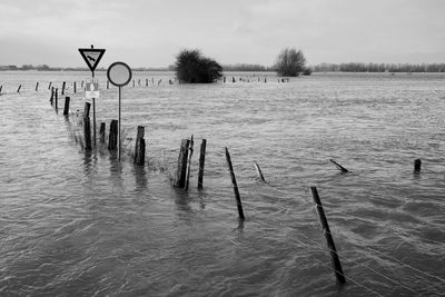 Wooden posts in water against sky