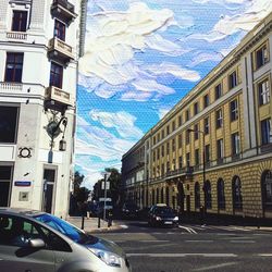 Cars on city street against sky