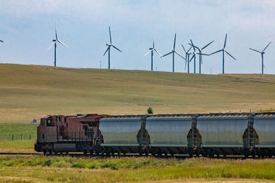 Windmills on field against sky