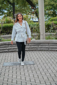 Portrait of young woman walking on footpath