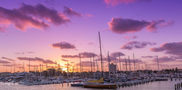 Boats moored at harbor against sky during sunset