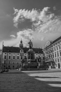 Statue in city against sky