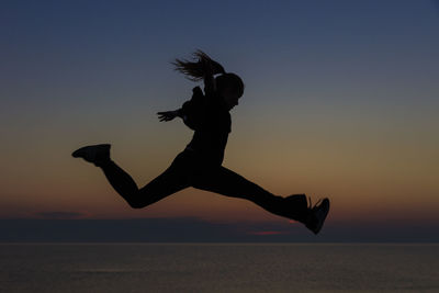 Silhouette girl jumping at beach against sky