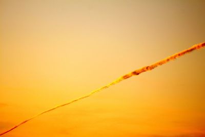 Low angle view of orange sky with vapor trail
