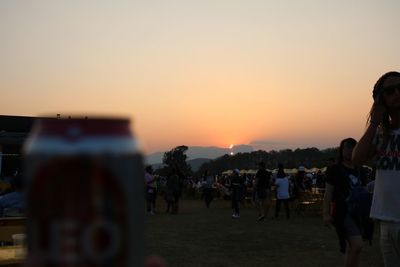People on beach against sky during sunset