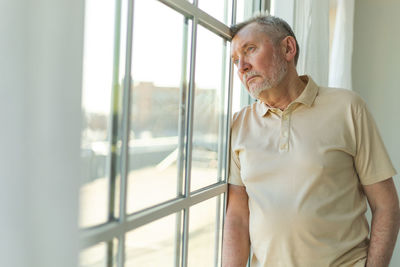 Side view of young man looking through window