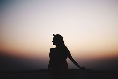 Silhouette of woman standing against sky during sunset