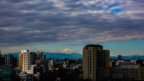 Buildings in city against cloudy sky