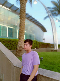 Portrait of young man standing against trees