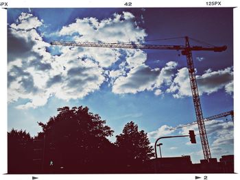 Low angle view of crane against cloudy sky