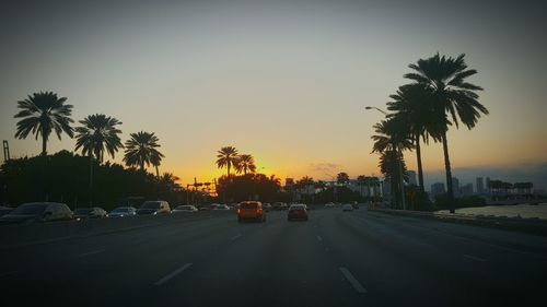 Cars on road against sky during sunset