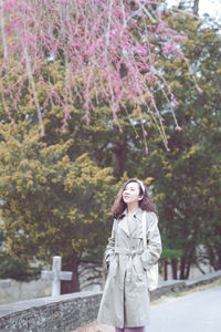 Young woman standing against trees