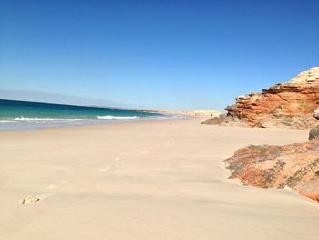 Scenic view of beach against clear blue sky