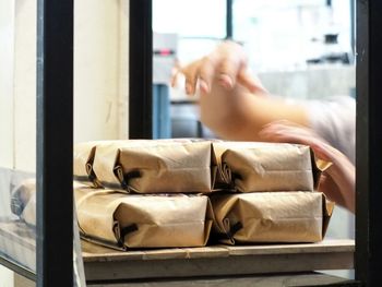 Cropped image of woman arranging packages in shelf