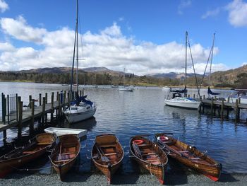 Boats moored at harbor against sky