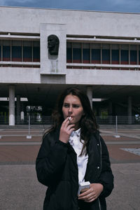 Portrait of beautiful woman standing against building