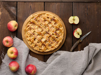 Round baked apple pie on a brown wooden table, top view