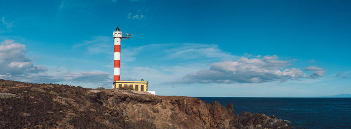 Lighthouse by sea against sky