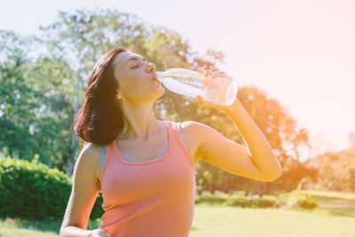 Midsection of woman drinking drink against sky