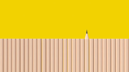 Close-up of yellow pencils against wall