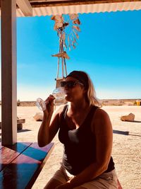 Woman sitting by table and drinking wine