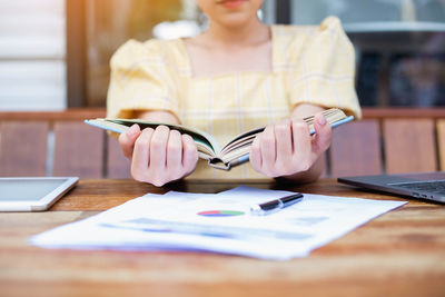 Midsection of woman holding smart phone on table