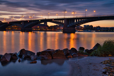 Bridge over river against sky at sunset