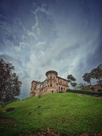 Old ruin building in field against cloudy sky