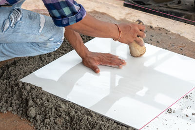 Midsection of worker fixing tile