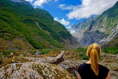 Rear view of woman looking at mountains against sky