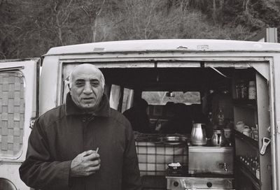 Portrait of man standing by camper van