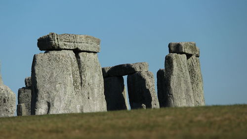 Low angle view of stone structure on field against clear sky