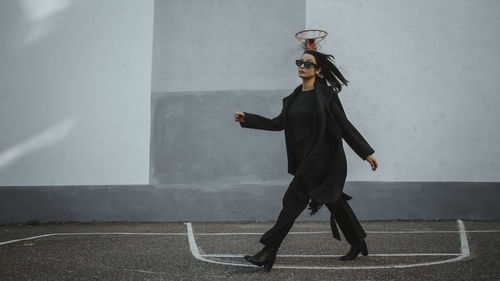 Beautiful woman wearing sunglasses walking outdoors against wall