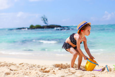 Boy holding umbrella on beach against sky