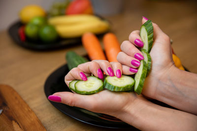 Cropped hands of woman holding vegetables on table
