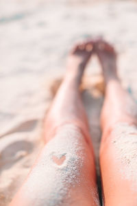 Low section of person lying on sand