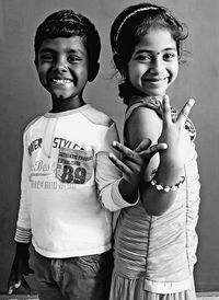 Portrait of smiling siblings standing against wall