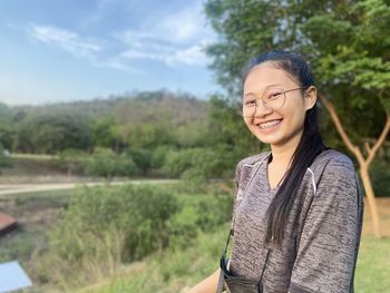 Portrait of smiling young woman standing against plants