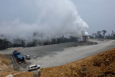 Smoke emitting from factory against sky