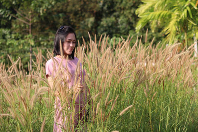 Smiling young woman standing amidst grass