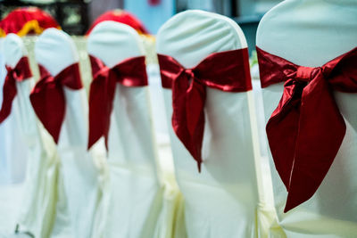 Red ribbons on white chairs arranged during wedding