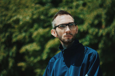 Portrait of young man standing against trees