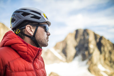Side view of mountaineer wearing red jacket and climbing helmet.